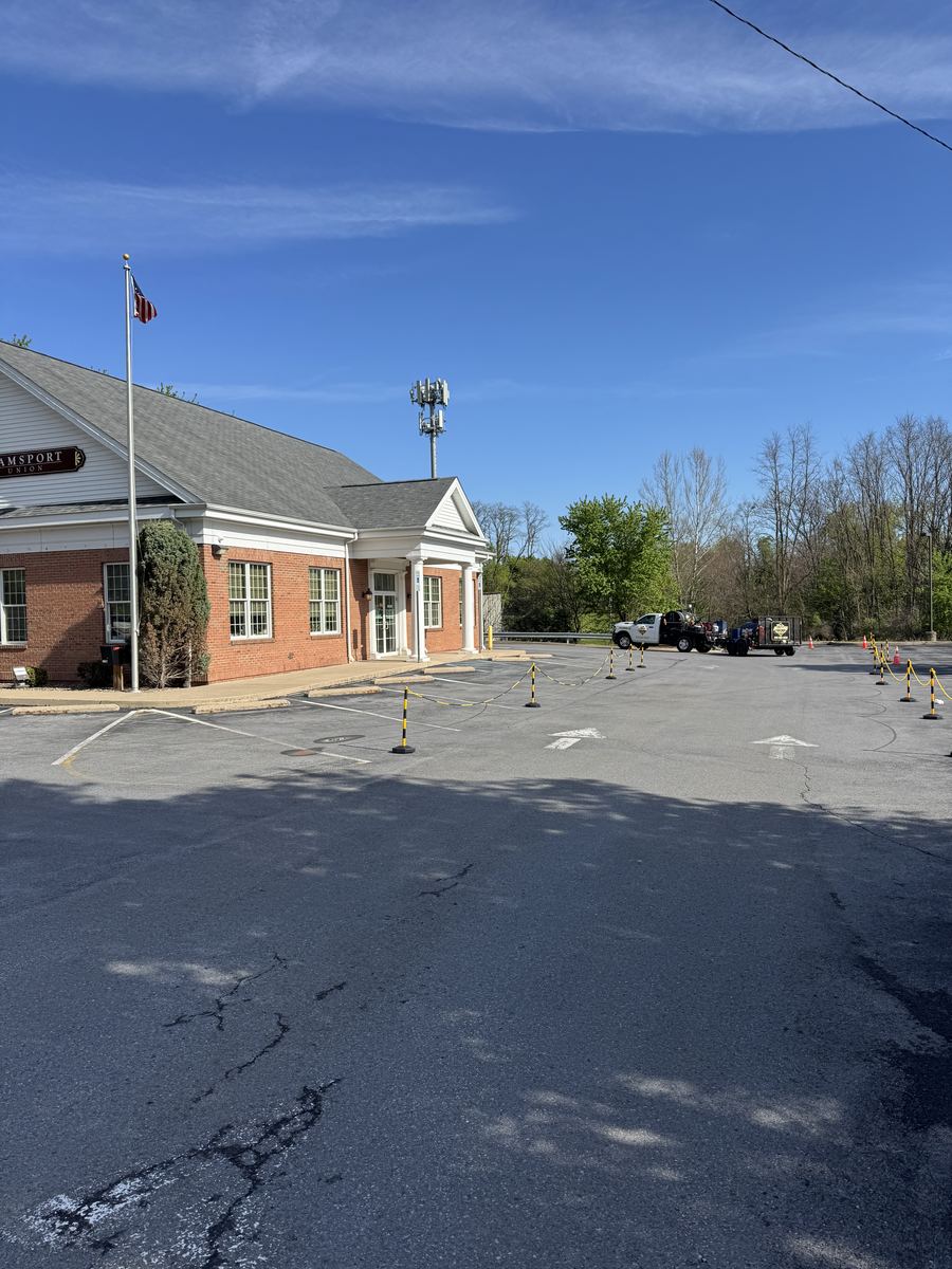 Before sealcoating – credit union parking lot with cracks and fading